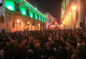 Demonstrators wave flags during a protest against a government decision to tax calls made on messaging applications on October 17, 2019, outside the government palace in Beirut. (AFP)