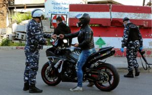 A police officer fines a cyclist for violating lockdown in central Beirut, Lebanon, March 22. (AFP)