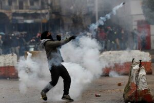 A protester throws back a tear gas canister towards riot policemen during a protest in Tripoli. (AP)