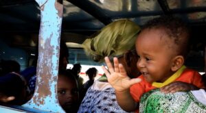 An Ethiopian refugee who fled Tigray region holds a child inside a courtesy bus at the Fashaga camp, as they are transferred to Um-Rakoba camp on the Sudan-Ethiopia border, in Kassala state, Sudan. (Reuters)