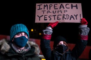 A woman wearing a protective mask holds a sign during the Get him out! defend democracy rally, a day after supporters of US President Donald Trump stormed the Capitol, in the Brooklyn borough of New York City, New York, US, on January 7, 2021. (Reuters)