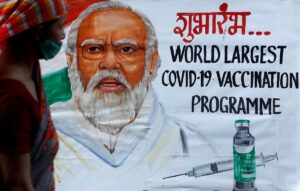 A woman walks past a painting of Indian Prime Minister Narendra Modi a day before the inauguration of the COVID-19 vaccination drive on a street in Mumbai, India, on January 15, 2021. (Reuters)