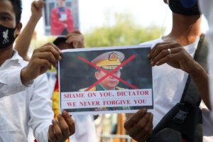 Myanmar citizens hold a picture of Myanmar's army chief Min Aung Hlaing with his face crossed out after the military seized power in a coup in Myanmar, outside United Nations venue in Bangkok, Thailand February 3, 2021. (Reuters)