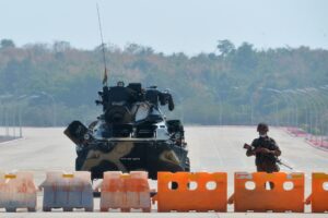 A soldier stands guard on a blockaded road to Myanmar's parliament in Naypyidaw on February 1, 2021, after the military detained the country's de facto leader Aung San Suu Kyi and the country's president in a coup. STR / AFP