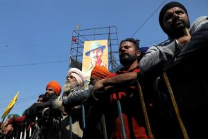 People stand behind a barrier at the site of a protest where farmers are protesting against farm laws, at Singhu border, in New Delhi, India, on January 27, 2021. (Reuters)