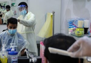 A barber wears a protective face shield and gloves as he cuts hair of a customer at a local barber shop in Riyadh. (File photo: Reuters)