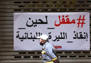 A man walks past a closed shopping center in Sidon, Lebanon March 16, 2021. The Arabic reads: Closed until the Lebanese Lira is rescued. Picture taken March 16, 2021. (Reuters)