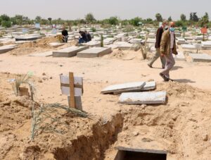 Palestinians walk past a grave dug for a coronavirus disease (COVID-19) victim, at a cemetery, east of Gaza City April 20, 2021. Picture taken April 20, 2021. (Reuters)