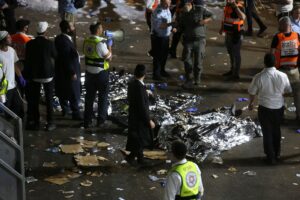 Ultra-Orthodox Jewish men stand next to covered bodies after dozens of people were killed and others injured after a grandstand collapsed in Meron, Israel, where tens of thousands of people were gathered to celebrate the festival of Lag Ba'omer at the site in northern Israel early on April 30, 2021. (File photo: AFP)