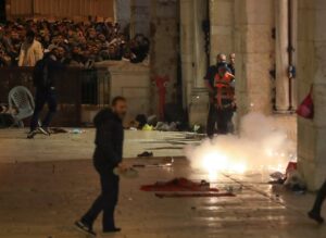 Palestinians react as Israeli police fire stun grenades during clashes at the compound that houses Al-Aqsa Mosque. (Reuters)